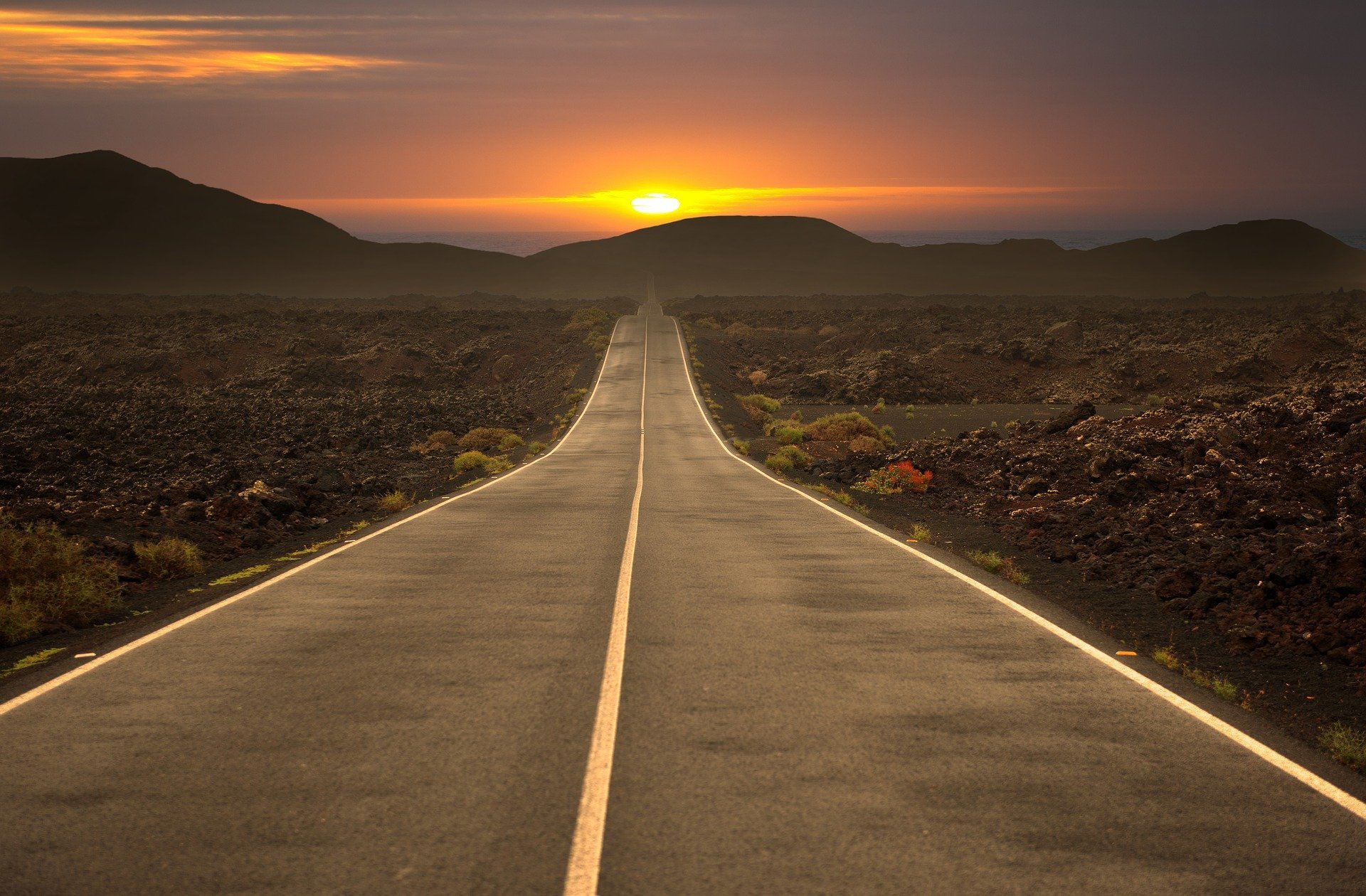 Road leading towards sunset over mountain
