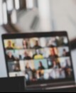 Blurred laptop screen showing people on a virtual meeting