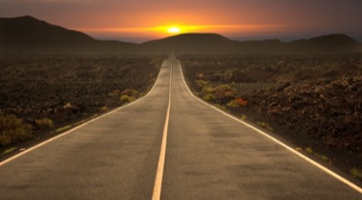 Road leading towards sunset over mountain