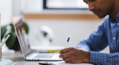 Man sitting at laptop writing